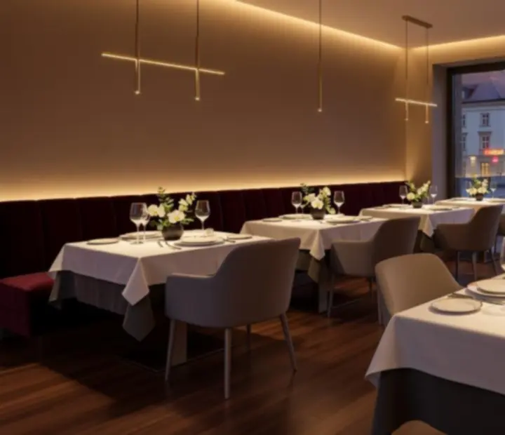 Widok eleganckiej sali restauracyjnej Vel Krago z nakrytymi stołami i nastrojowym oświetleniem.